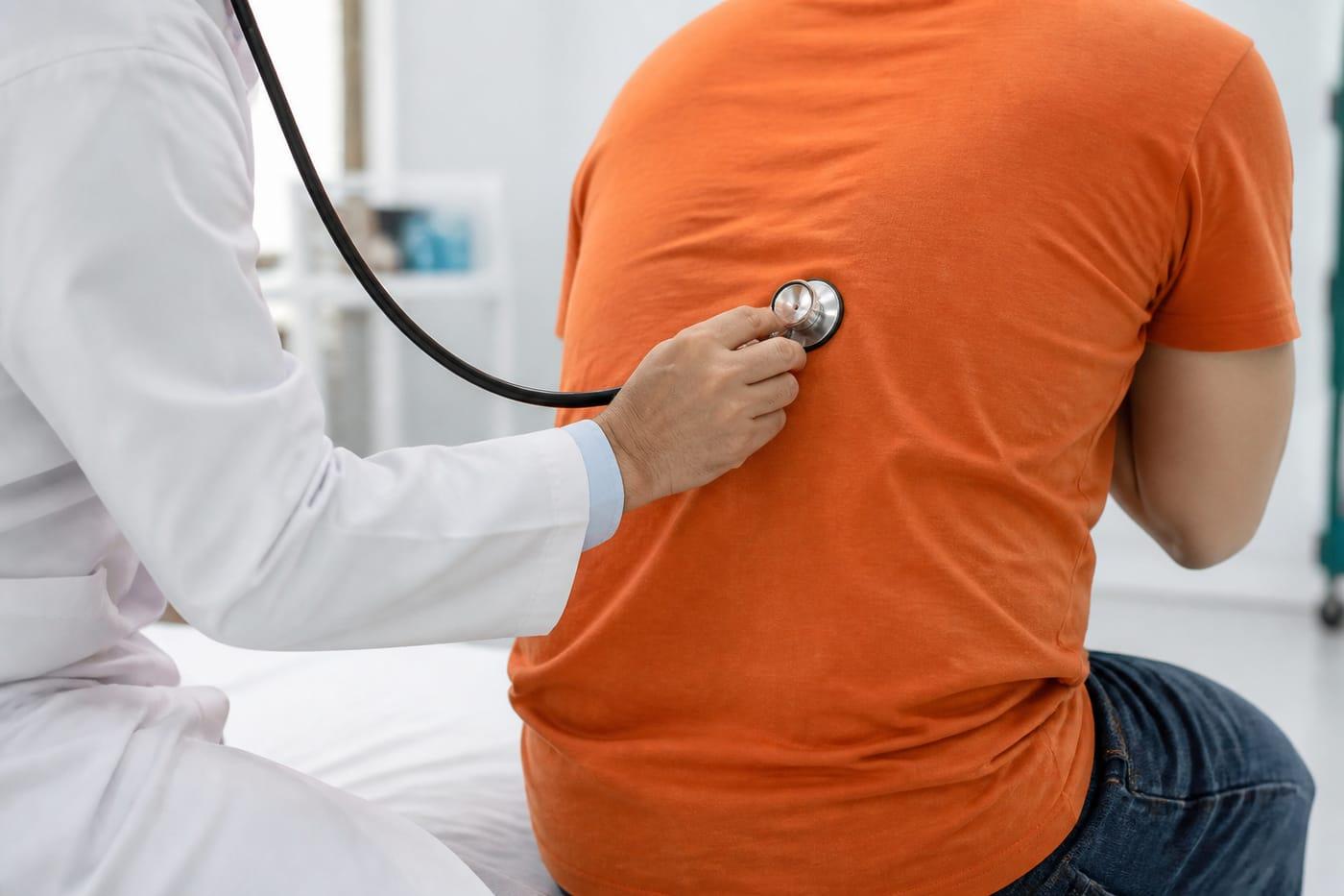 Clinical lung exam with stethoscope on back, faces not shown